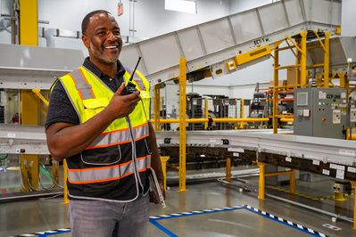 Corporate photographer rendition of a service team supervisor talking on walkie talkie inside a large logistics facility