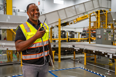 Corporate photographer rendition of a service team supervisor talking on walkie talkie inside a large logistics facility