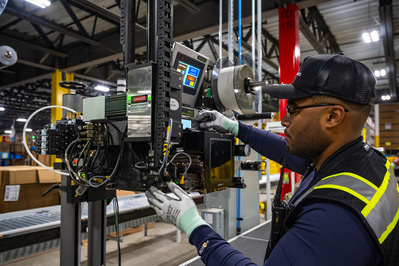 Skilled service technician inspecting printing equipment in a distribution and logistics warehouse