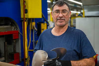 Male production line operator posing in front of his equipment