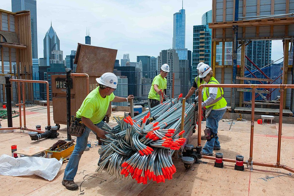 Construction crew maneuvering on top of a high-rise in Chicago