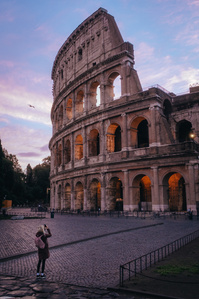 A tourist photographs the Colosseum at sunrise in Rome, Italy.