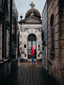 Young boy in red wanders through Recoleta Cemetery in Buenos Aires, Argentina. 