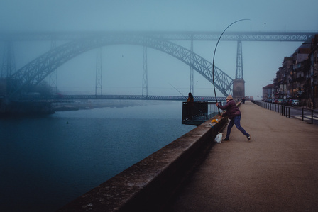 A fisherman casts a line into the Duoro River in front of the Dom Luís I Bridge on a foggy Sunday morning in Porto, Portugal.
