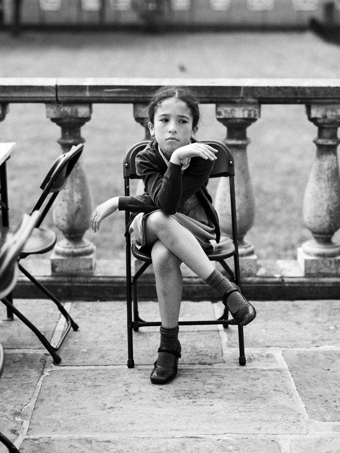 young girl sat on chair in front of old wall on an estate in south London 