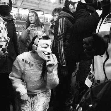A female masked protester crouches down and sneaks a look through a crowd, witnessing an arrest made on Regent Street, London. During the 