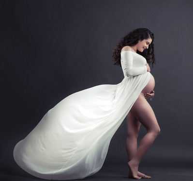 A pregnant young woman poses in a studio for her photoshoot