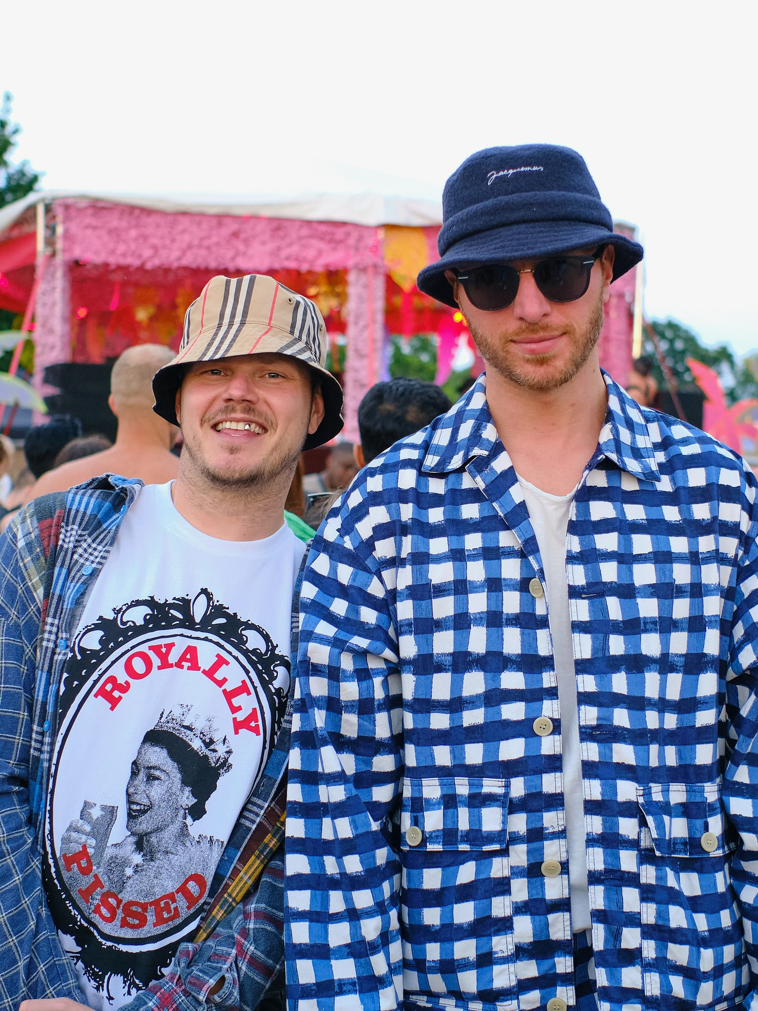two stylish LGBTQ+ people wearing bucket hats pose for a street portrait
