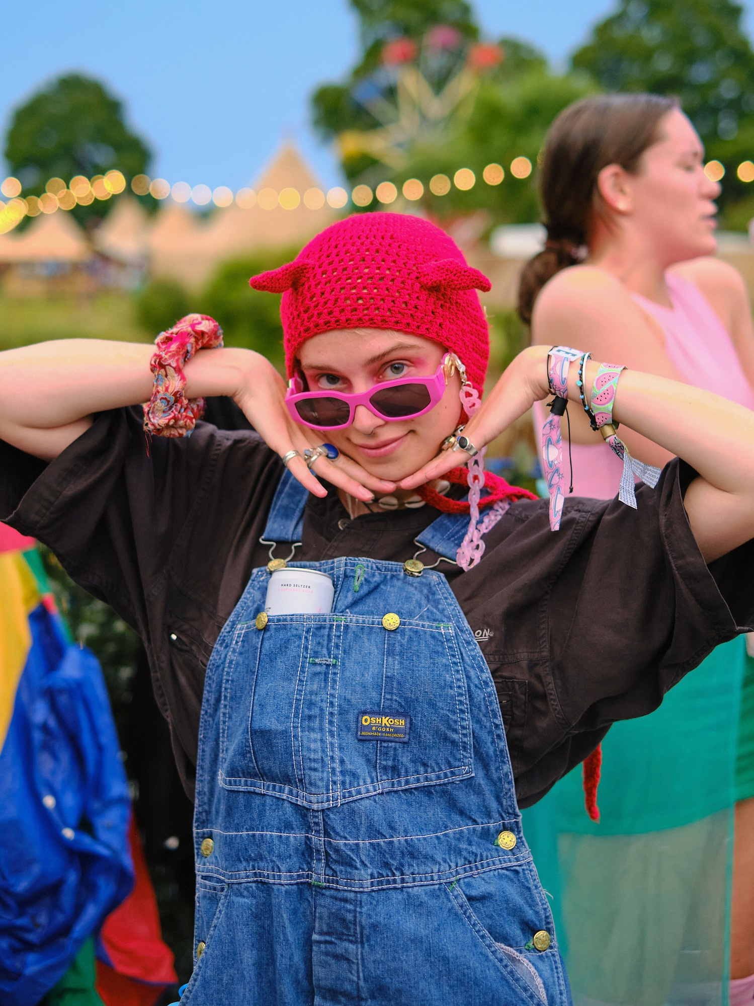 a cute young woman poses in dungarees and a hat with ears for a street portrait