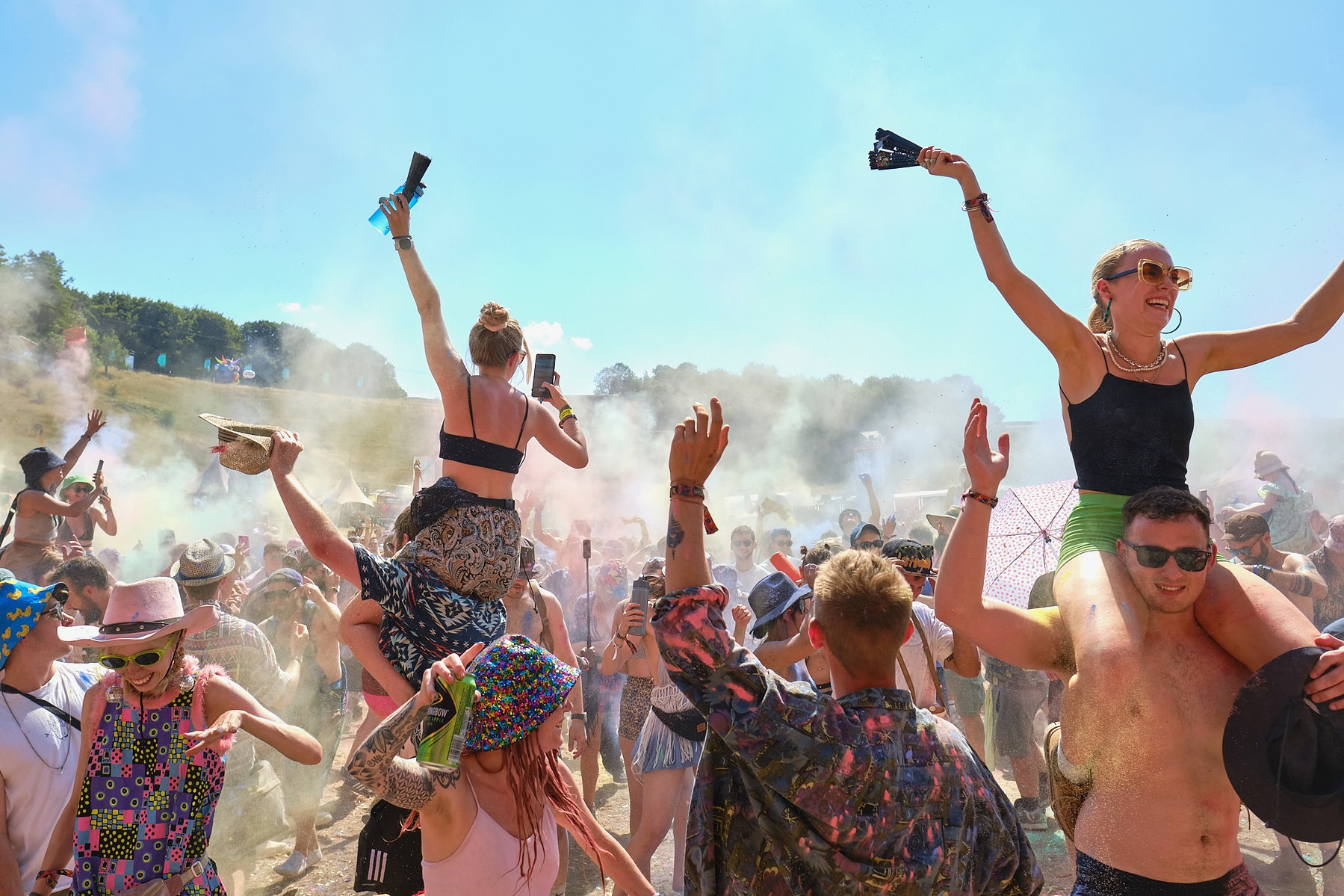 people throw their hands in the air and dance in the sun at Boomtown 2023