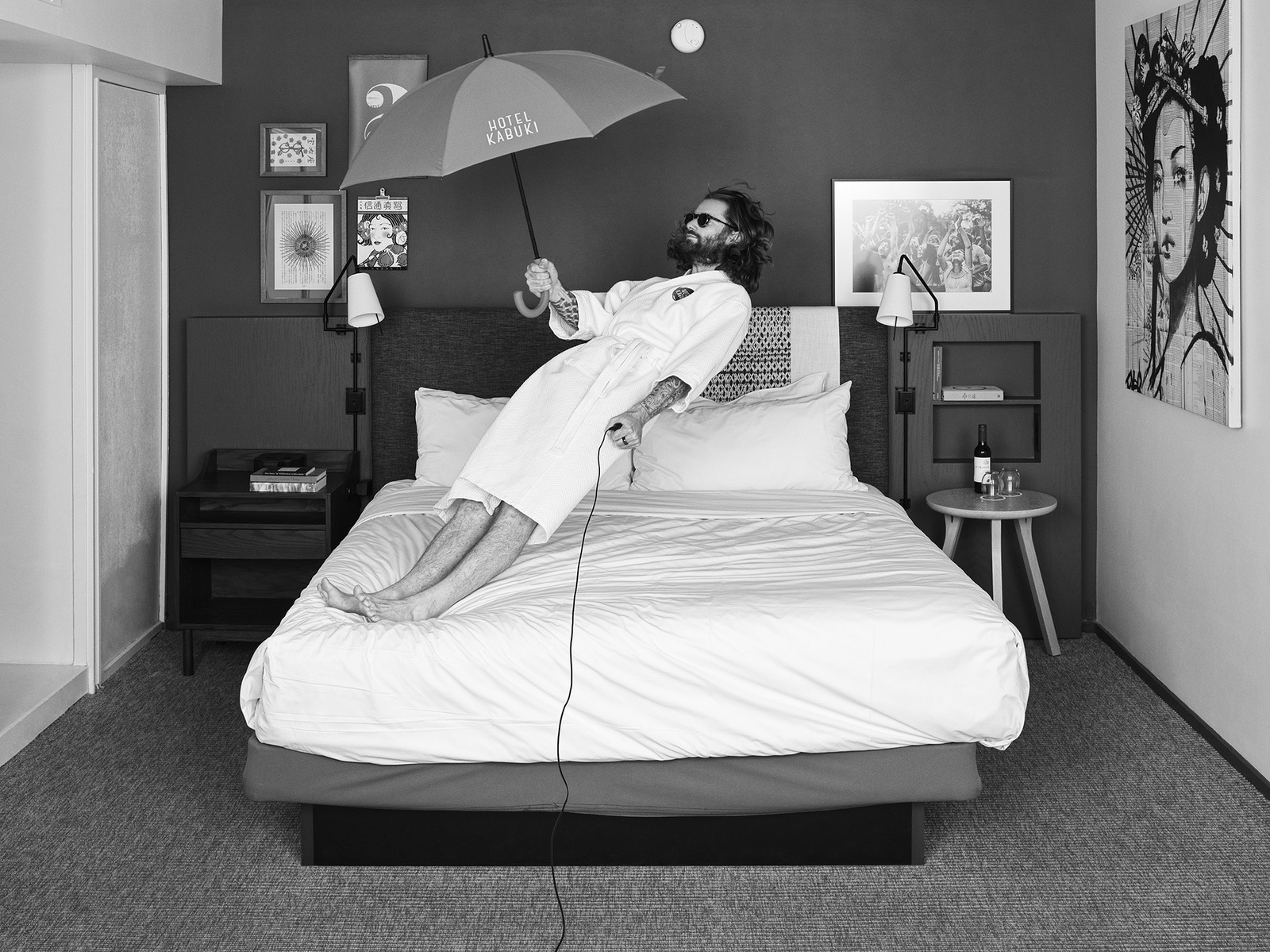 Man in white robe balancing on hotel bed, holding Hotel Kabuki umbrella, surrounded by framed artwork
Hasselblad Flexbody 50 CFV ii. "Suspended Moments" - The delicate balance between comfort and adventure in transient spaces