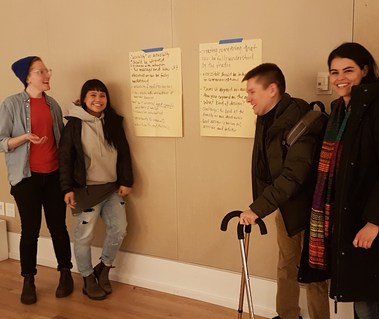 Group of people smiling in front large paper with notes. 