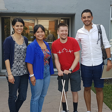 Four people smiling in front of a building