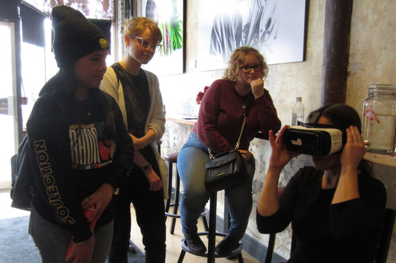 Three people looking at a person with a virtual reality headset on. 
