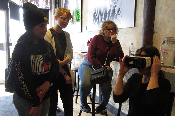 Three people looking at a person with a virtual reality headset on. 