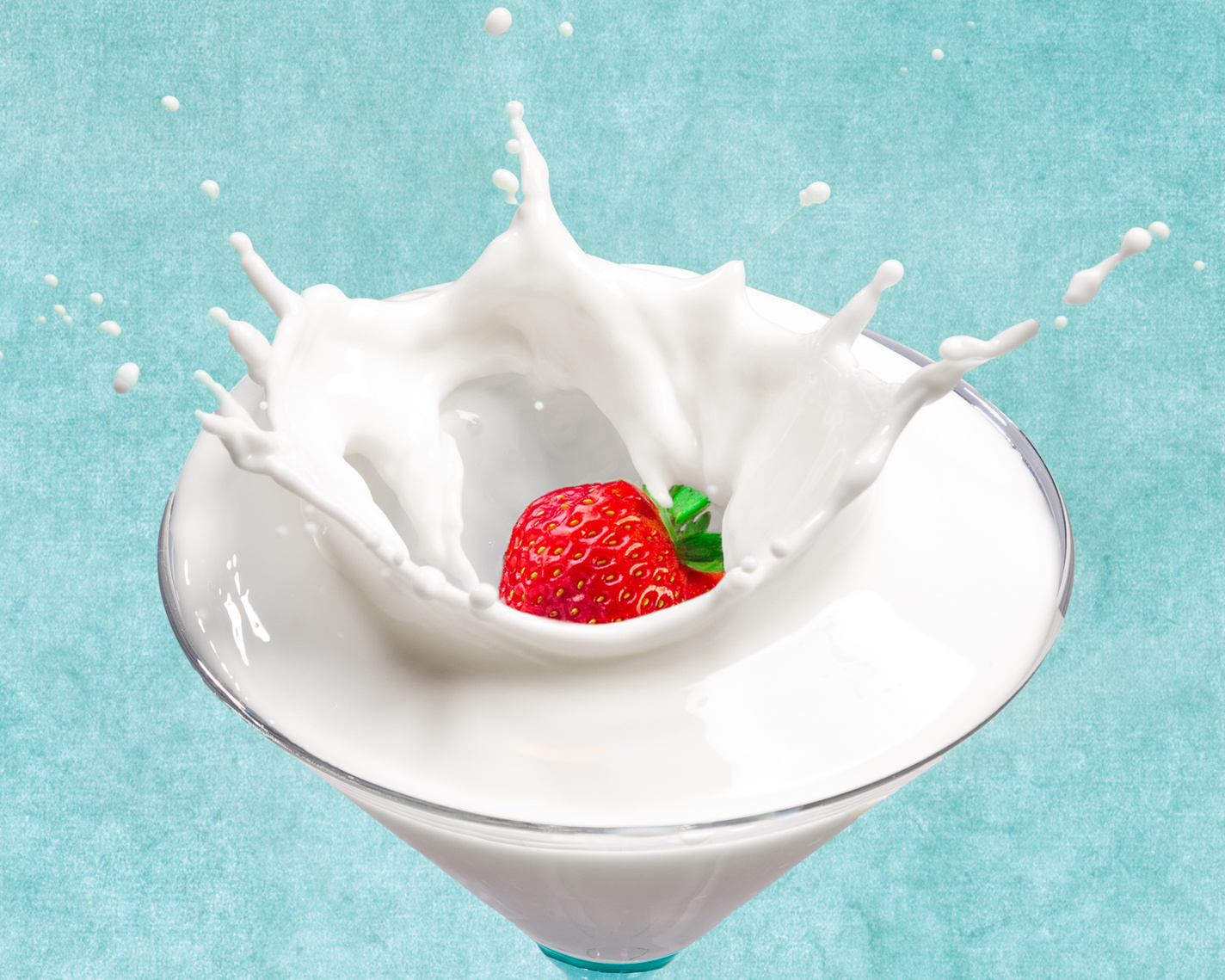 Strawberry falling into milk