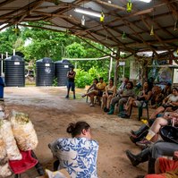 Photo of a class sitting in front of guest speaker for a university course,  Natural Building and Carnival Architectonics part of the international program at OCAD University. Taken by Leilah Dhoré at Wa Samaki Ecosystems in Freeport,Trinidad and Tobago. 