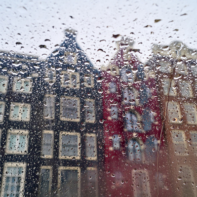 Amsterdam famous canal homes through rain on glass of canal tour boat