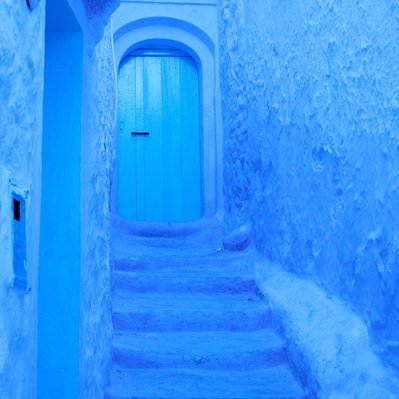 Moroccan  landscape photograph featuring a blue door in the city of Chefchaouen. 