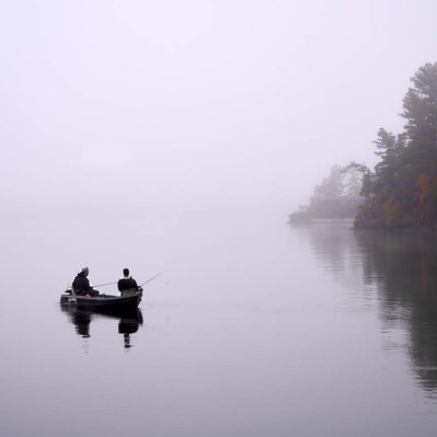 A small boat with fishermen in a foggy morning in a lake found in the Canadian Shield of Canada