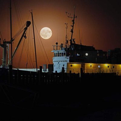 A warm full moon  rising above the Namao research vessel in Gimli harbour, Manitoba.