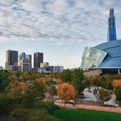 The Canadian Museum for Human Rights with Winnipeg skyline behind it during fall.