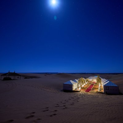 Moroccan landscape photograph featuring a desert camp lit by moonlight near Merzouga