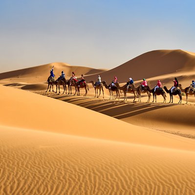 Moroccan landscape photograph featuring a camel caravan into the desert.