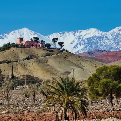 Moroccan landscape photograph featuring a hilltop fortress overlooking the Atlas Mountains.