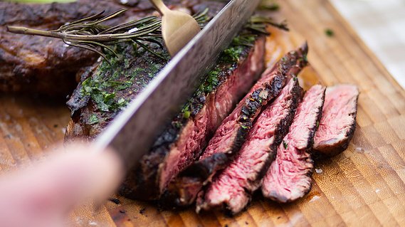 A knife slicing juicy, red, Dorset steak.