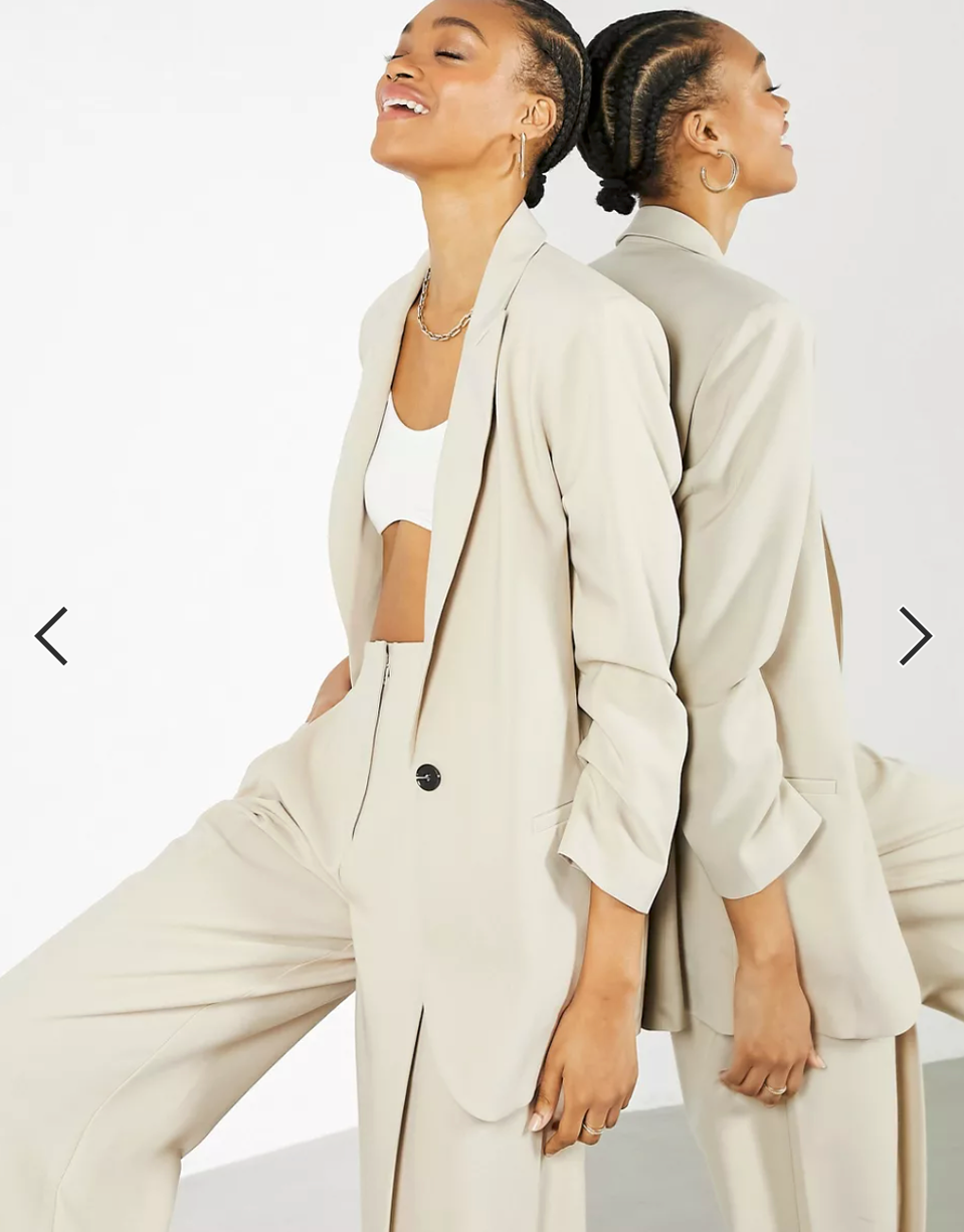 woman leaning against a mirror wearing a jacket top and pants