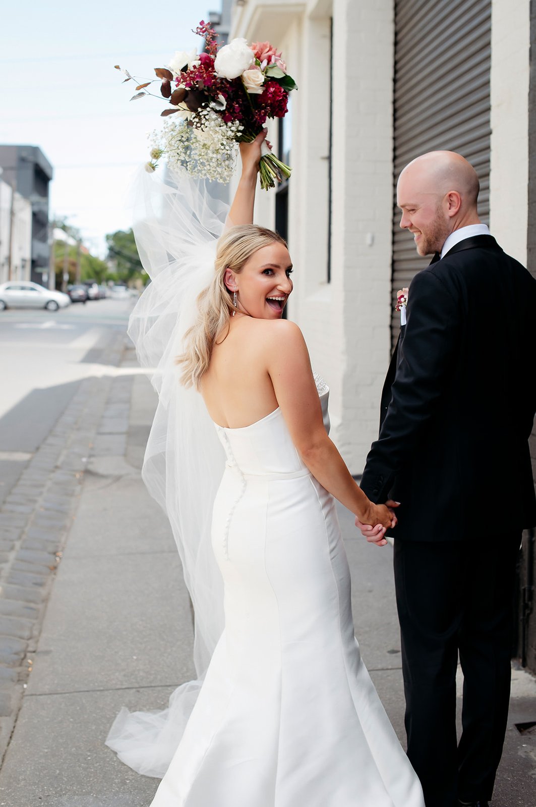 Bride and groom looking back with bride holder her bouquet high above her head