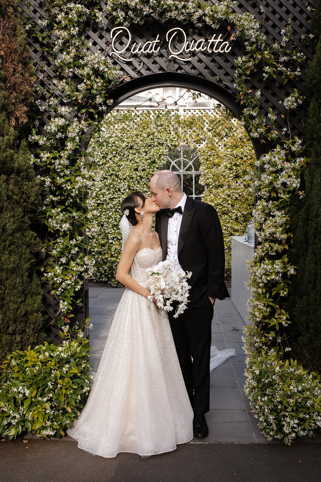 bride and groom kissing under a quat quatta sign 