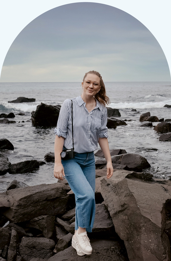 Melbourne wedding photographer portrait. A smiling woman looking into the camera, with black rocks and the sea in the background.