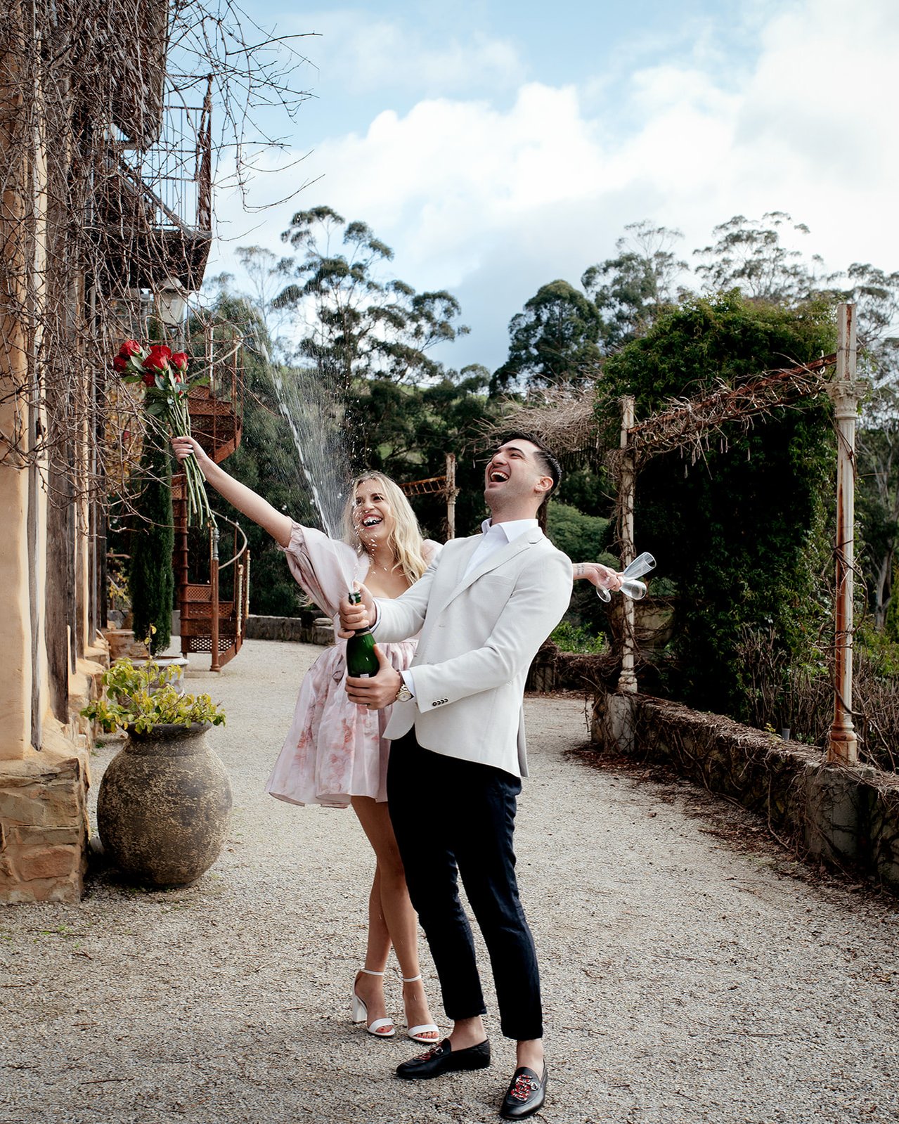 A couple popping a bottle of champange laughing