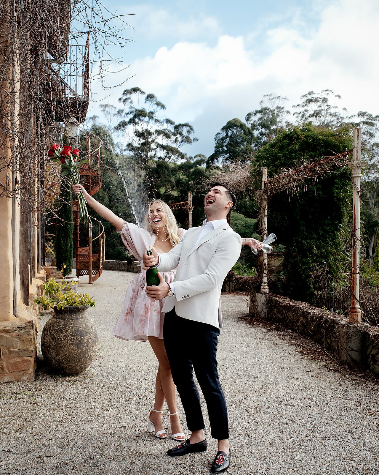 A couple popping a bottle of champange laughing