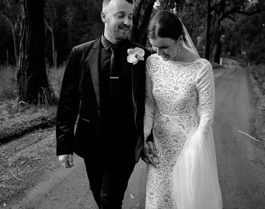 Bride and groom walking down road in black and white
