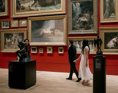 male and female walking holding hands look at old paintings in art gallery