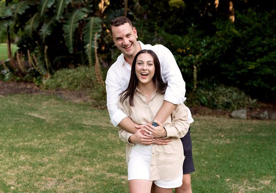 male and female hugging facing the camera laughing as they just got engaged 