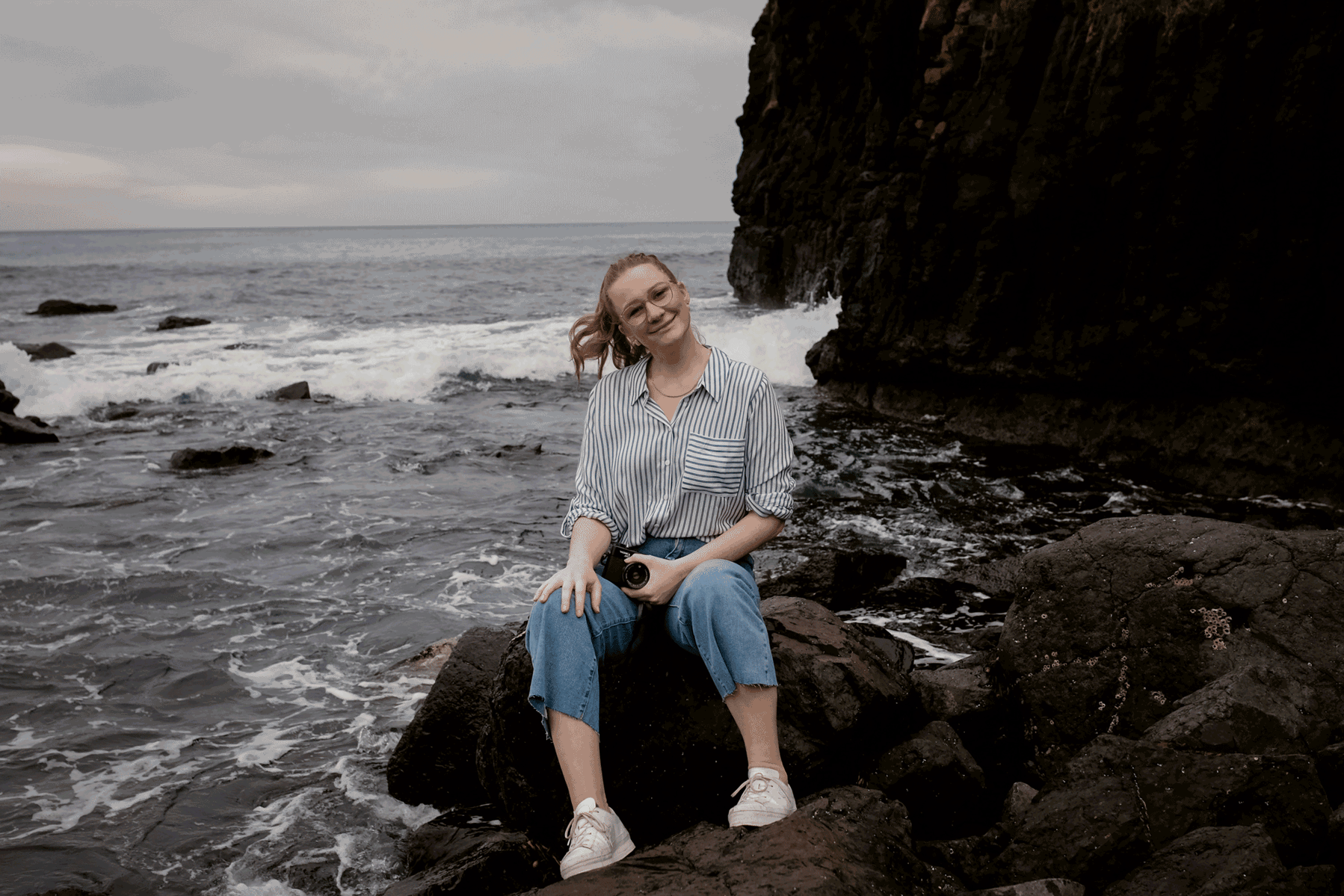 lady sitting on rock at beach moving 