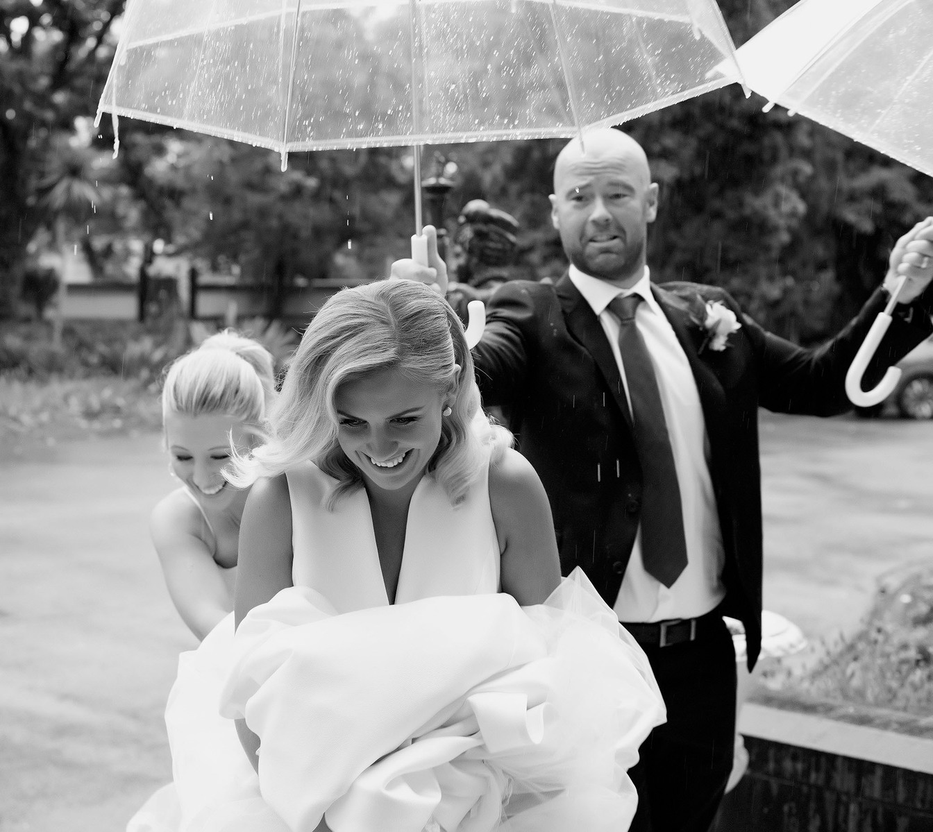 man holding two umbrellas lady smiling and holding dress