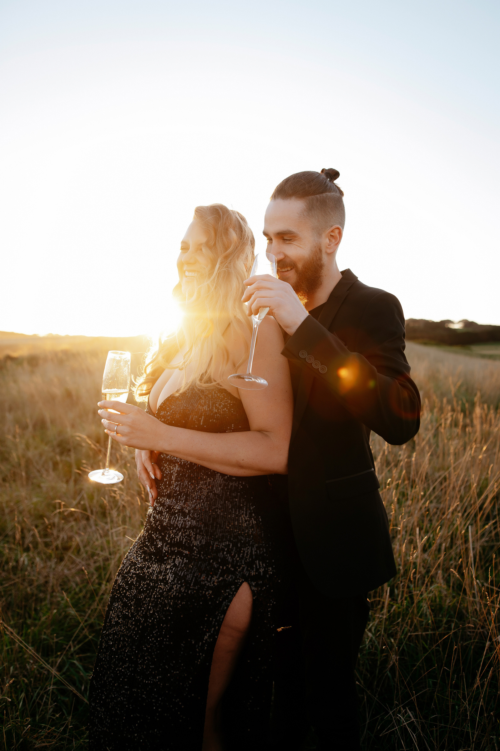 a couple with drinking champagne on sunset in field