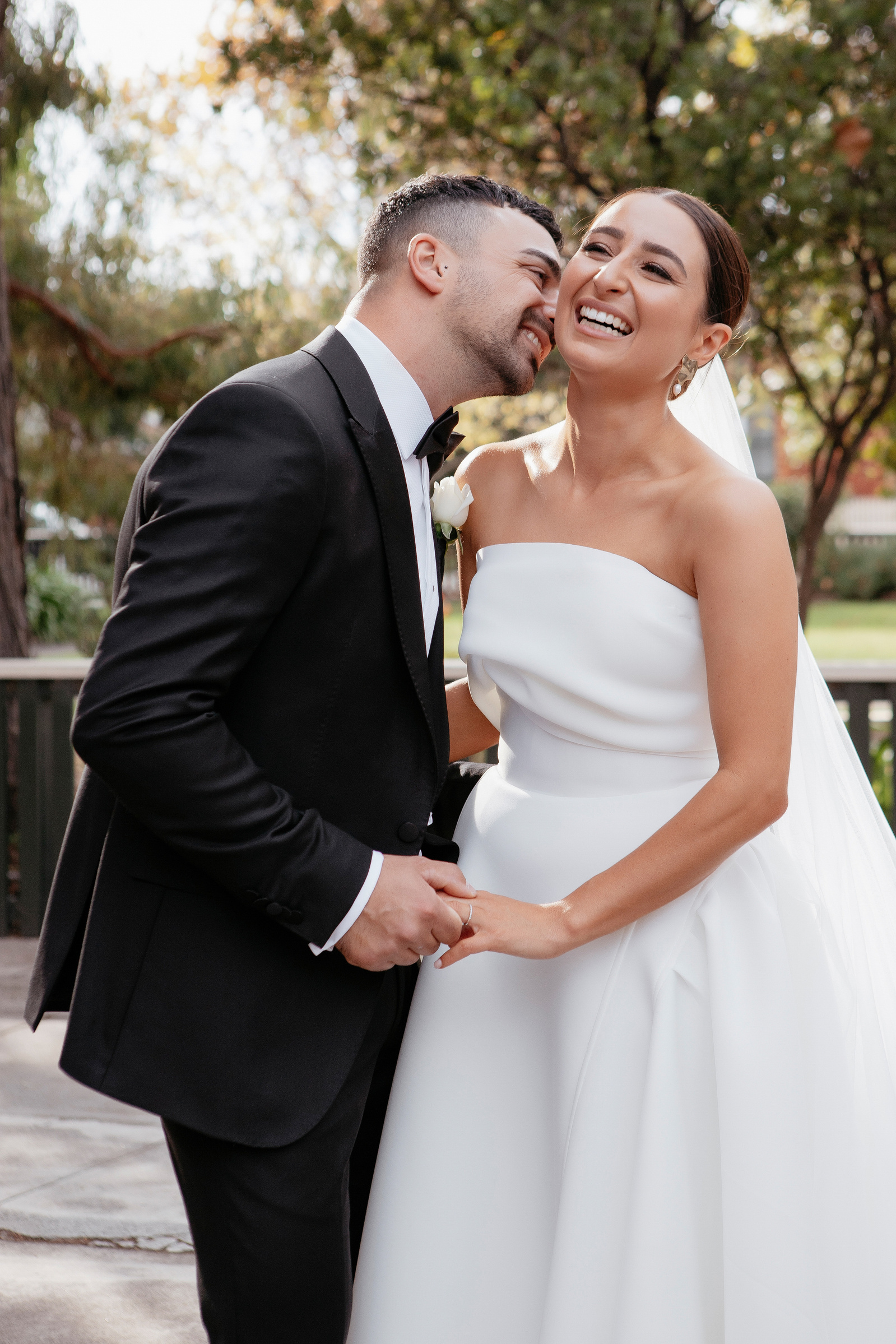 Groom whispering in brides ear while bride is laughing