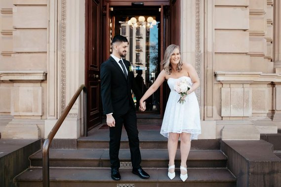 Couple standing on steps holding hands smiling