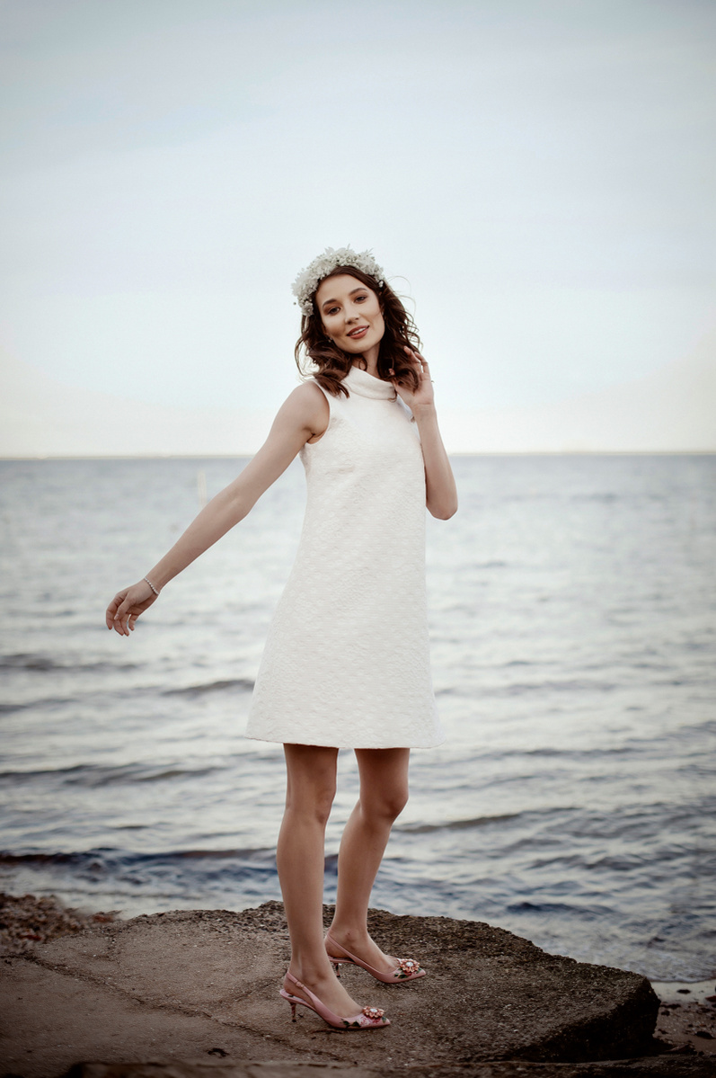 Lady standing on a rock in white dress with arms out