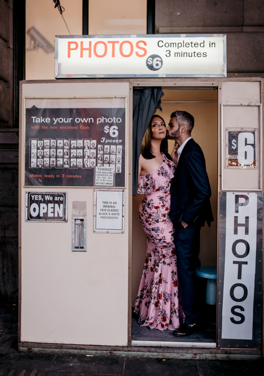 man kissing woman in pink dress on cheek inside a photo booth