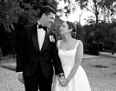 Black and white images of bride and groom. Bride holding one of grooms hands with her two hands looking at each other. 