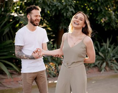 man holding woman's hand and arm looking at her. woman looking straight holding mans hand