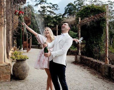 Couple celebrating. woman with hands in the air smiling and man has Champaign in his hands 