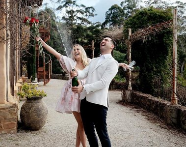 Couple celebrating. woman with hands in the air smiling and man has Champaign in his hands 